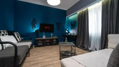 a living room with blue walls and a couch and a tv at Apartment at the foothills of Acropolis in Athens