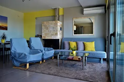 a living room with a blue couch and two chairs at Sandra's Sea View at Sounio in Sounio