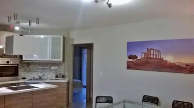 a kitchen with white cabinets and a table with chairs at Sandra's Sea View at Sounio in Sounio