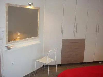 a room with a chair and a mirror and a cabinet at Sandra's Sea View at Sounio in Sounio