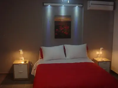 a bedroom with a red bed with two night stands at Sandra's Sea View at Sounio in Sounio