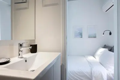 a white bathroom with a sink and a shower at Homz Studios Neapolis in Athens