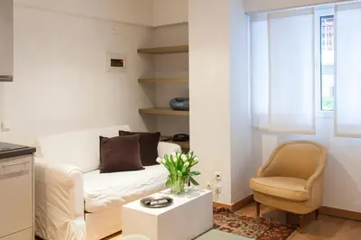 a living room with a white couch and a chair at Homz Studios Neapolis in Athens