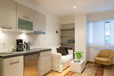 a kitchen and a living room with a couch at Homz Studios Neapolis in Athens