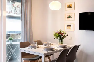 a dining room with a white table and chairs at Homz Studios Neapolis in Athens