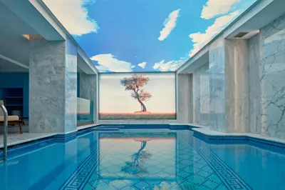 a swimming pool with a tree mural on the wall at Electra Metropolis in Athens