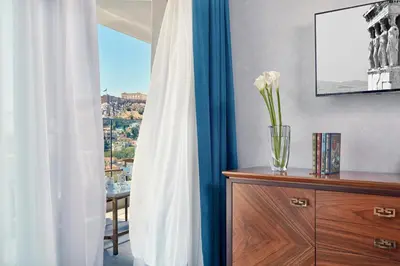 a vase of flowers on a dresser with a window at Electra Metropolis in Athens