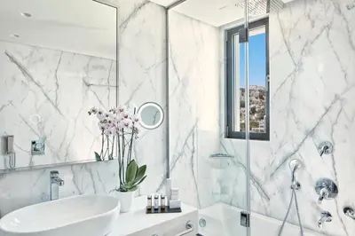 a white bathroom with a sink and a shower at Electra Metropolis in Athens