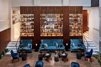 a library with blue couches and tables and books at Electra Metropolis in Athens