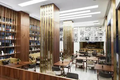 a restaurant with tables and chairs in a library at Electra Metropolis in Athens