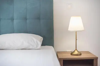 a bed with a white pillow and a lamp on a table at Victoria Secret Apartments in Athens