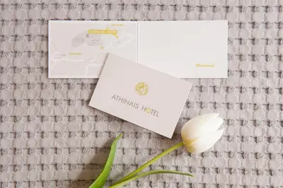a white flower and two envelopes on a table at Athinais Hotel in Athens