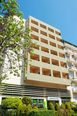 a large white building with bushes in front of it at Athinais Hotel in Athens