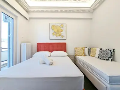 a bedroom with two beds and a red chair at Acropolis View Dream Apartments in Athens