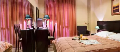 a hotel room with a bed and pink curtains at Nicola Hotel in Athens