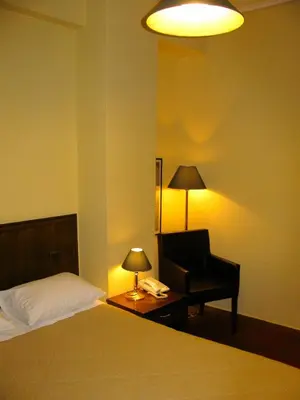 a bedroom with a bed and a chair and a lamp at Nicola Hotel in Athens