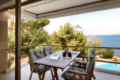 a table and chairs on a balcony with a view of the ocean at Kavouri Flat in Athens