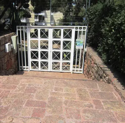 a white gate with a stone wall and a brick sidewalk at Kavouri Flat in Athens