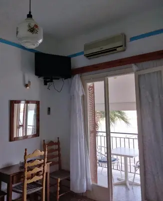 a room with a door open to a balcony with a table at Svetlana & Michalis Oasis Hotel in Agia Marina Aegina