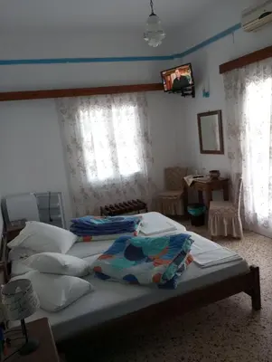 a bedroom with two beds and a table and windows at Svetlana & Michalis Oasis Hotel in Agia Marina Aegina