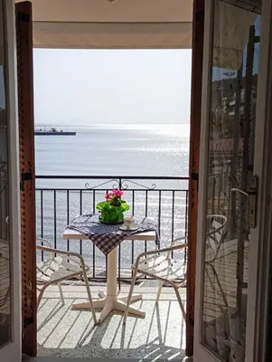 a table on a balcony with a view of the ocean at Svetlana & Michalis Oasis Hotel in Agia Marina Aegina