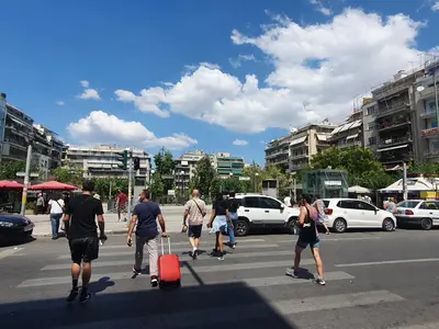a group of people walking in a parking lot with luggage at Pedion Areos Park 4 Center 4 in Athens