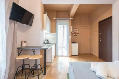 a kitchen and a living room with a table and stool at Studio Under Acropolis Rock in Athens