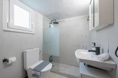 a white bathroom with a toilet and a sink at Studio Under Acropolis Rock in Athens