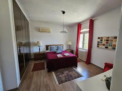 a bedroom with a bed and a window with red curtains at Villa Emily in Lagonissi