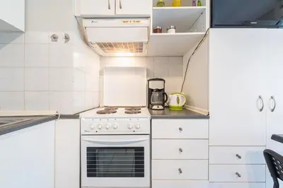 a small kitchen with white cabinets and an oven at Zenios Kisamos-Pretty comfy studio in Athens
