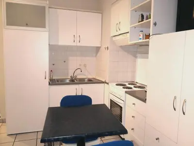 a kitchen with white cabinets and a table and a sink at Zenios Kisamos-Pretty comfy studio in Athens