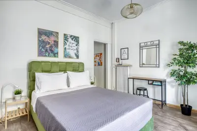 a bedroom with a bed with a green headboard and a table at Studio in The Heart of Acropolis in Athens