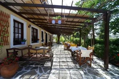 a patio with tables and chairs under a wooden pergola at Vagia Traditional, Aegina Island in Vaia