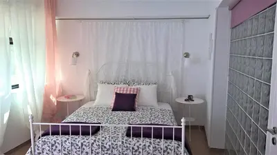 a small bedroom with a white bed and two tables at Driopon Apartment in Athens