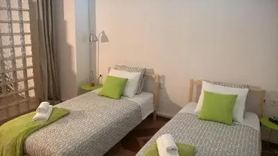 two beds in a small room with green pillows at Driopon Apartment in Athens