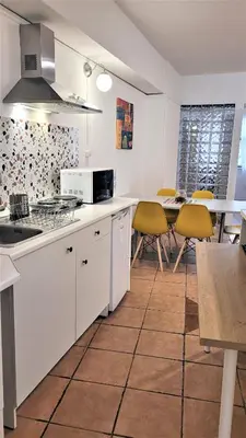 a kitchen with white cabinets and a table with yellow chairs at Driopon Apartment in Athens