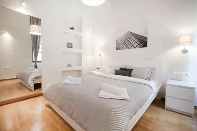 a white bedroom with a large bed with two towels on it at Central Apartments in Psiri - Athens in Athens