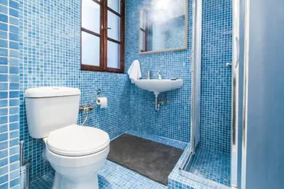 a blue tiled bathroom with a toilet and a sink at Central Apartments in Psiri - Athens in Athens