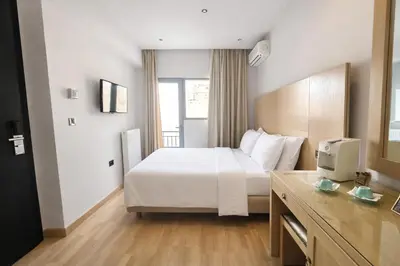 a hotel room with a white bed and a television at Areos in Athens