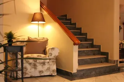 a living room with a chair and a staircase at Achillion Hotel in Athens