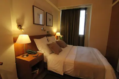 a bedroom with a bed with a phone on a night stand at Achillion Hotel in Athens