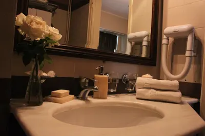 a bathroom sink with a vase of flowers and a mirror at Achillion Hotel in Athens