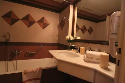 a bathroom with a sink and a mirror and a tub at Achillion Hotel in Athens