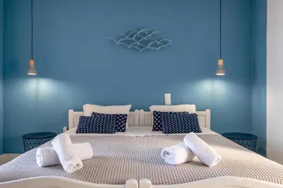 a blue bedroom with two beds with towels on them at Pefkides Aegina Boutique Apartments in Agia Marina Aegina
