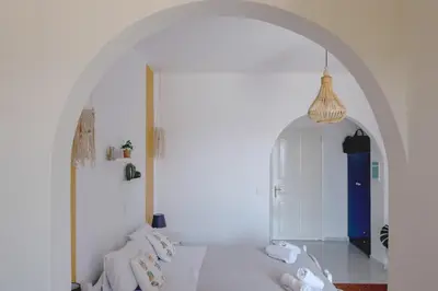 a white room with an archway and a blue door at Pefkides Aegina Boutique Apartments in Agia Marina Aegina
