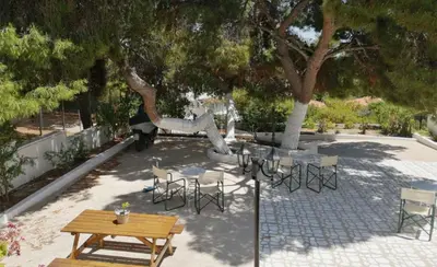 a patio with a table and chairs under a tree at Pefkides Aegina Boutique Apartments in Agia Marina Aegina