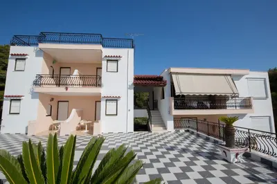 a large white house with a checkered floor at Pefkides Aegina Boutique Apartments in Agia Marina Aegina