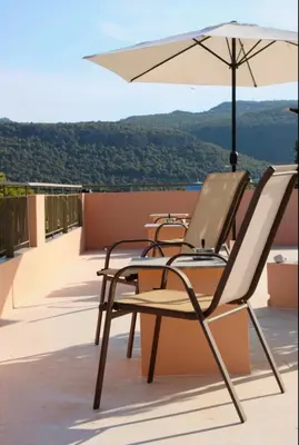 two chairs and an umbrella on a balcony at Hermes in Agia Marina Aegina