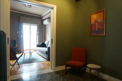a living room with green walls and a red chair at The Belgian Connection in Koukaki in Athens