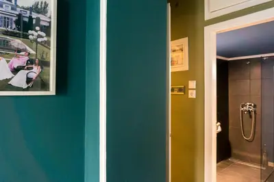 a bathroom with a green wall with a picture and a shower at The Belgian Connection in Koukaki in Athens